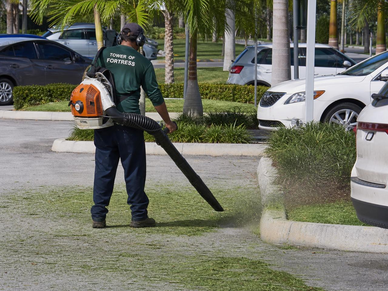 Landscaper blowing grass clippings off a commercial parking lot in South Florida